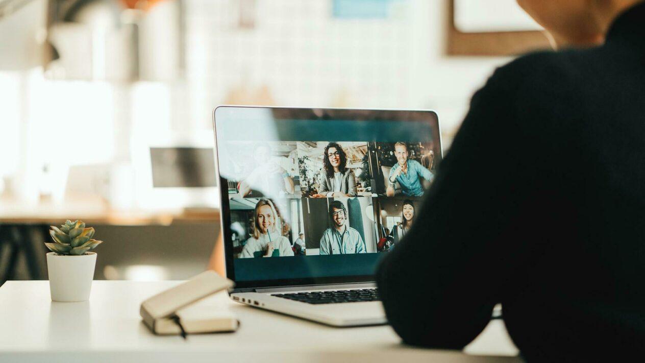 Person sitzt am Laptop und nimmt an einer Videokonferenz teil